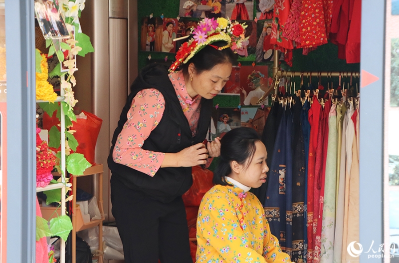 泉州府文廟附近，一名店主正為過(guò)路游客梳理頭發(fā)以佩戴“簪花圍”。人民網(wǎng) 黃東儀攝