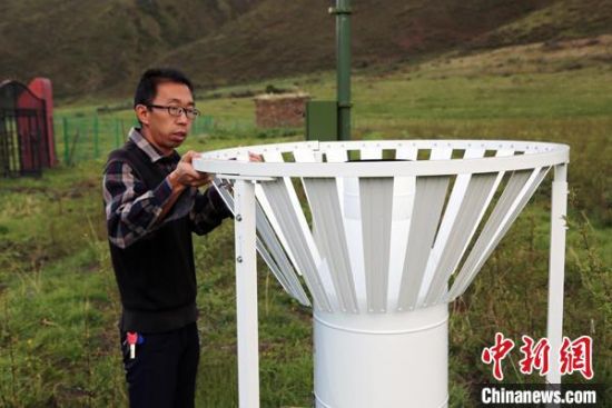 圖為班瑪縣氣象局工作人員在維護(hù)藏雪茶基地氣候站。青海省氣象局供圖