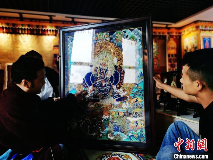 圖為久美尖措(左)與徒弟們展示唐卡作品?！?zhí)砀?攝