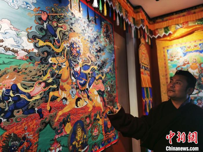 圖為久美尖措展示唐卡作品?！?zhí)砀?攝