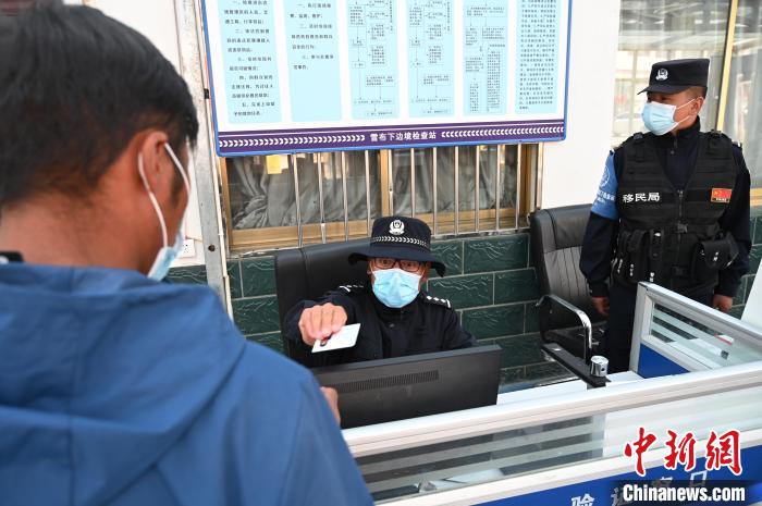 圖為移民管理警察登記完身份信息后將證件歸還給行人?！≮w朗 攝