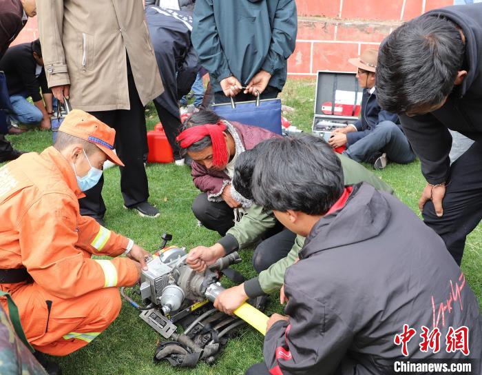 圖為森林消防員為護(hù)林員講解滅火裝備的使用方法?！〔际猩窒乐ш?duì) 供圖