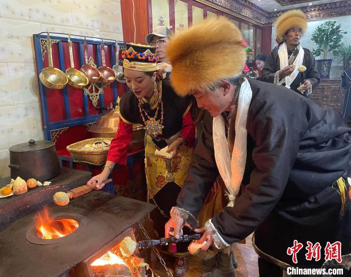 圖為人們在火上烤節(jié)日美食“結(jié)達(dá)”?！∪轿木?攝
