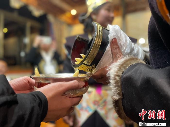 圖為主人在碗中斟滿青稞酒?！∪轿木?攝