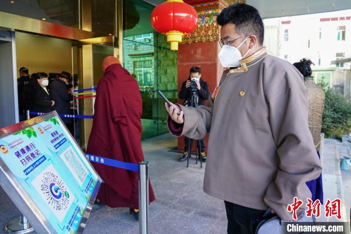 圖為政協(xié)委員掃場所碼進入會場?！〗w波 攝